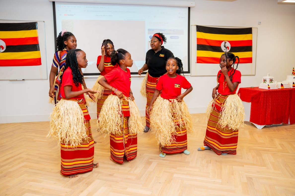 Dancers performing in traditional dress near Uganda flags